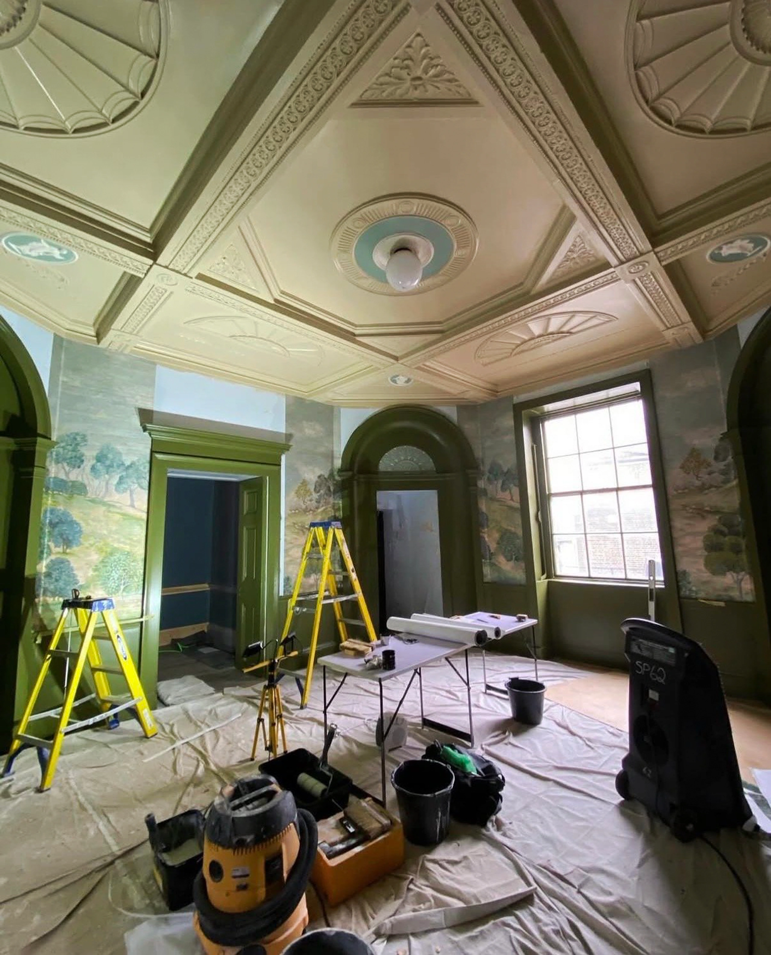 Heritage room with a decorative green ceiling, muralled walls and protective coverings during preparation