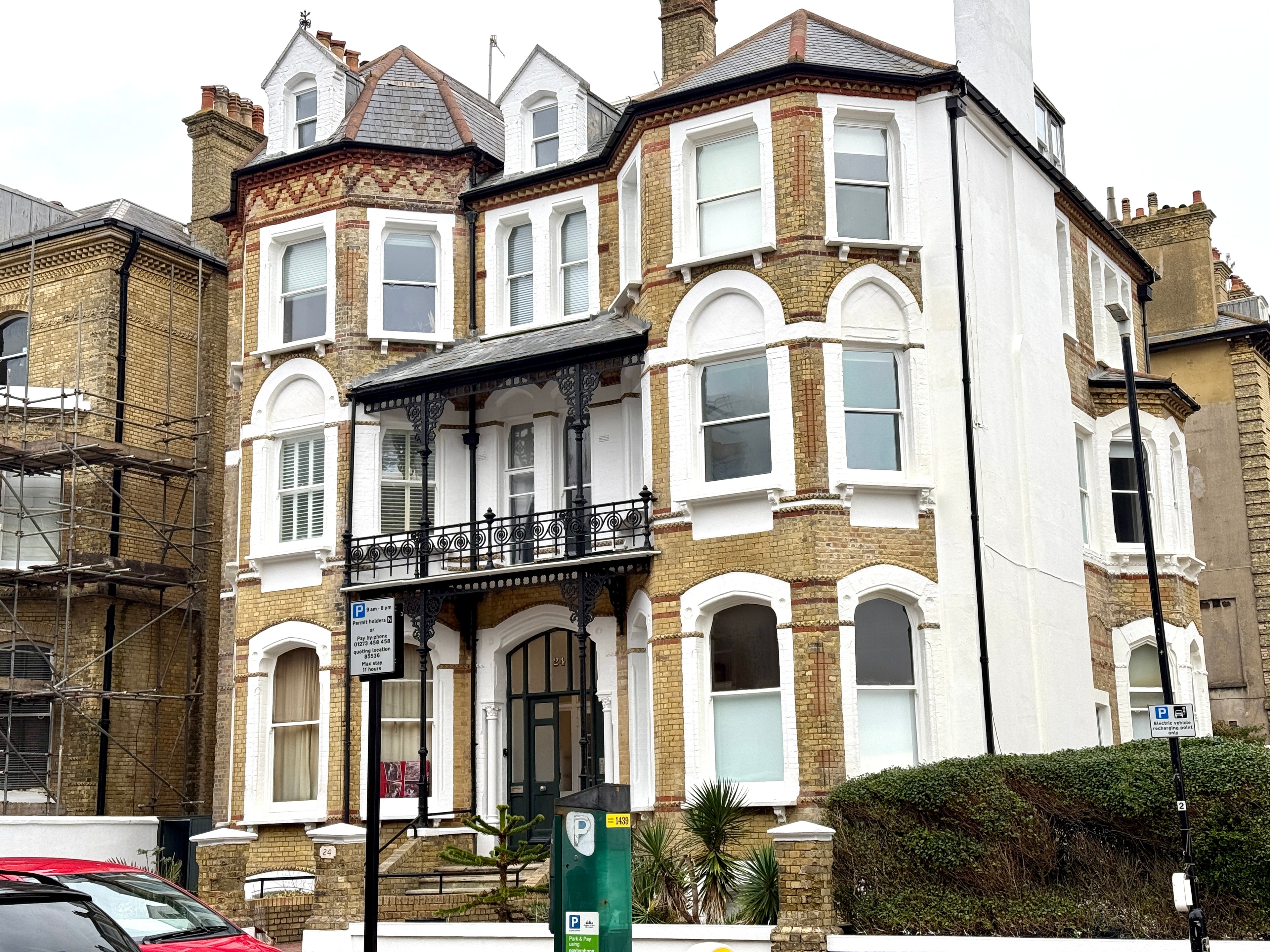 Completed period property exterior with restored white window surrounds, brickwork and black balcony railings